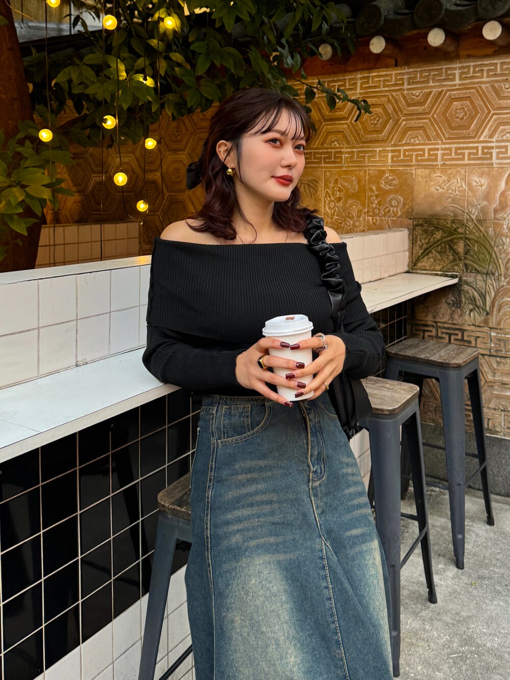 ブラック系のニット/セーター、ブラウン系のハンドバッグ、ブラック系のブーツを着用したレディースの秋コーディネートの5枚目の写真