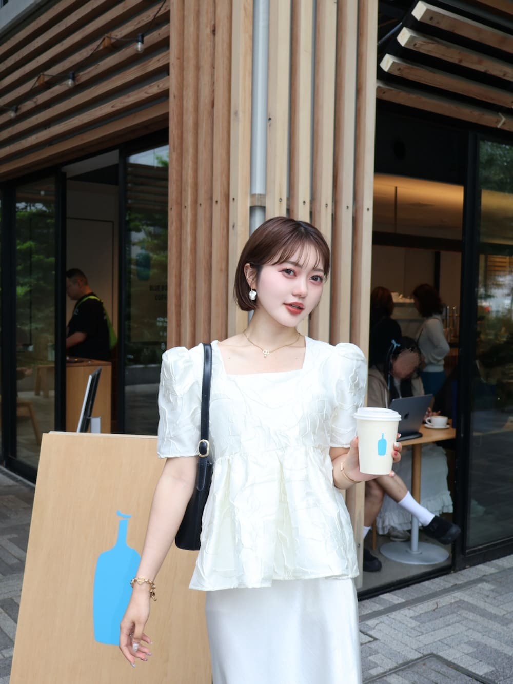 ホワイト系のシャツ/ブラウス、ホワイト系のスカート、ブラック系のパンプスを着用したレディースの夏コーディネートの2枚目の写真