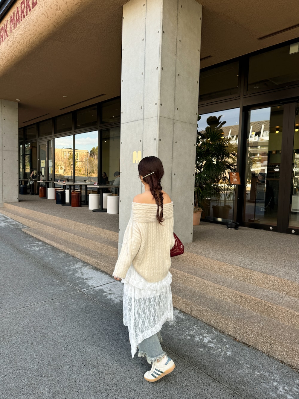 レッド系のハンドバッグ、ブルー系のデニムパンツを着用したレディースの冬コーディネートの4枚目の写真