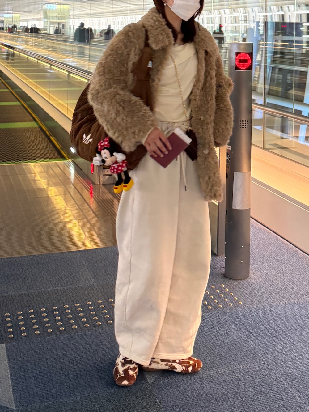 ブラウン系のスニーカー、ベージュ系のカバーオール、ホワイト系のニット/セーターを着用したレディースの冬コーディネートの3枚目の写真