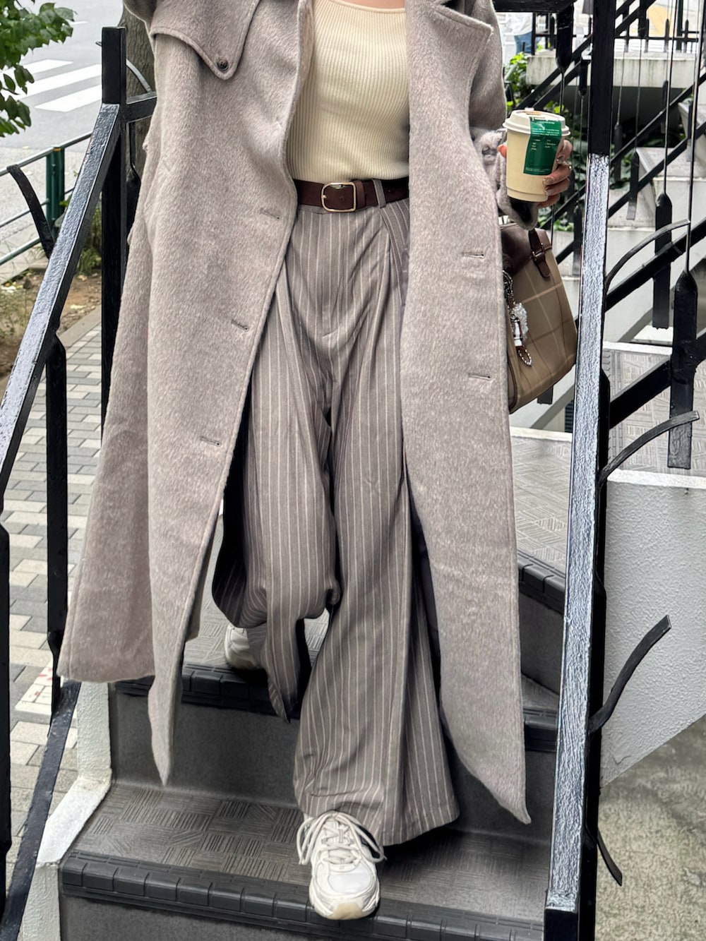 ブラウン系のステンカラーコート、ホワイト系のニット/セーター、ベージュ系のスニーカーを着用したレディースの秋コーディネートの5枚目の写真