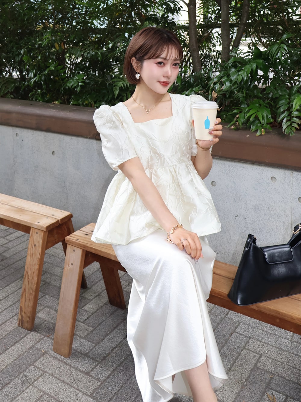ホワイト系のシャツ/ブラウス、ホワイト系のスカート、ブラック系のパンプスを着用したレディースの夏コーディネートの4枚目の写真