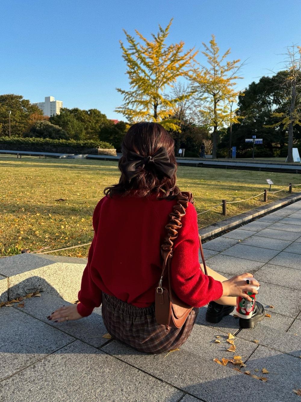 ブラウン系のスカート、レッド系のニット/セーター、ブラック系のブーツを着用したレディースの秋コーディネートの4枚目の写真