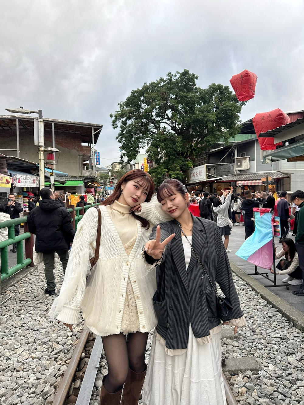 グレー系のテーラードジャケット、ホワイト系のカーディガン/ボレロ、ブラウン系のブーツを着用したレディースの冬コーディネートの2枚目の写真