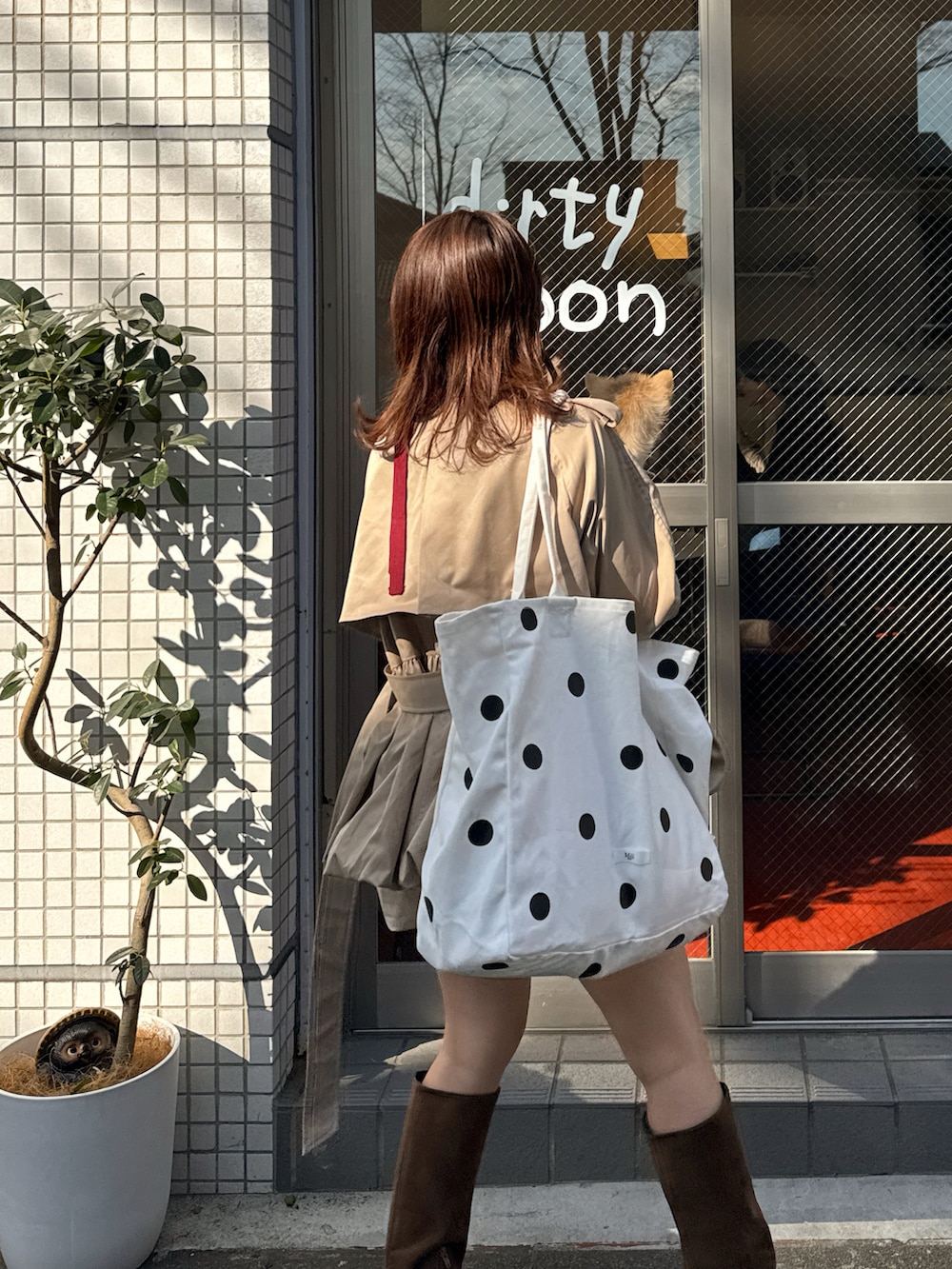 ベージュ系のトレンチコート、レッド系のニット/セーター、ブラウン系のブーツを着用したレディースの春コーディネートの3枚目の写真