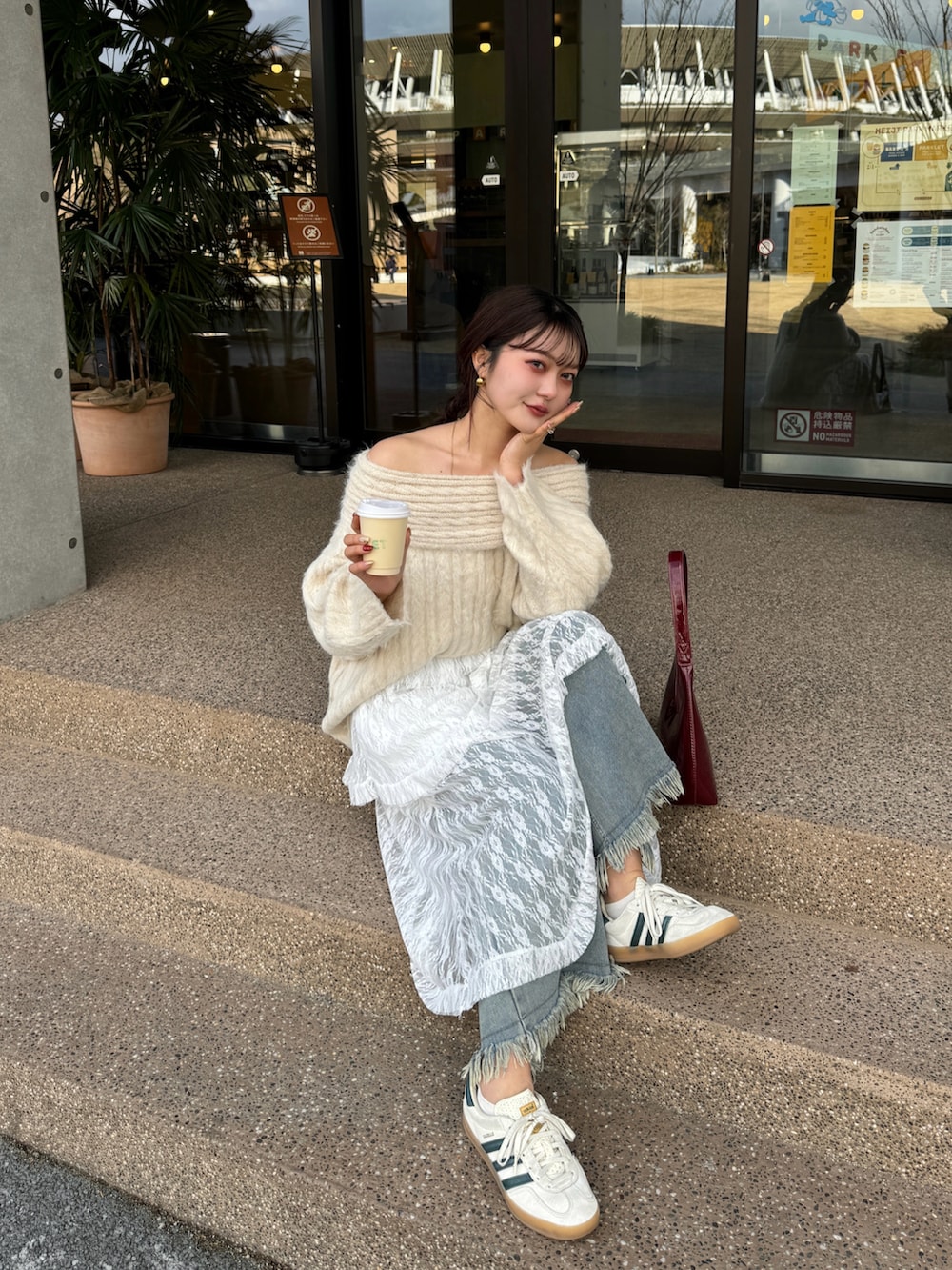 レッド系のハンドバッグ、ブルー系のデニムパンツを着用したレディースの冬コーディネートの3枚目の写真