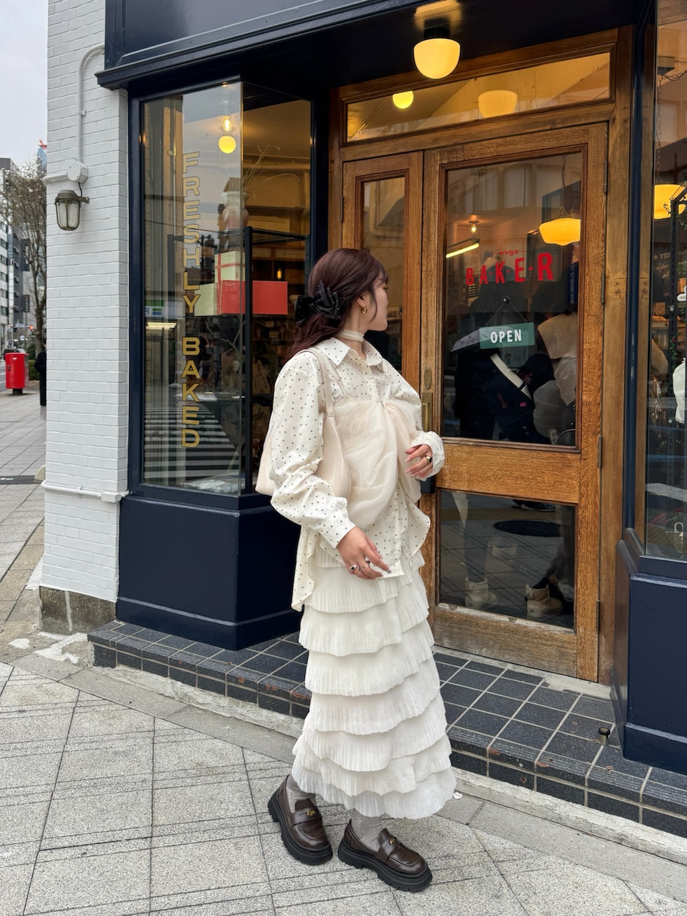 レッド系のハンドバッグ、ベージュ系のスカート、ホワイト系のシャツ/ブラウスを着用したレディースの春コーディネートの2枚目の写真