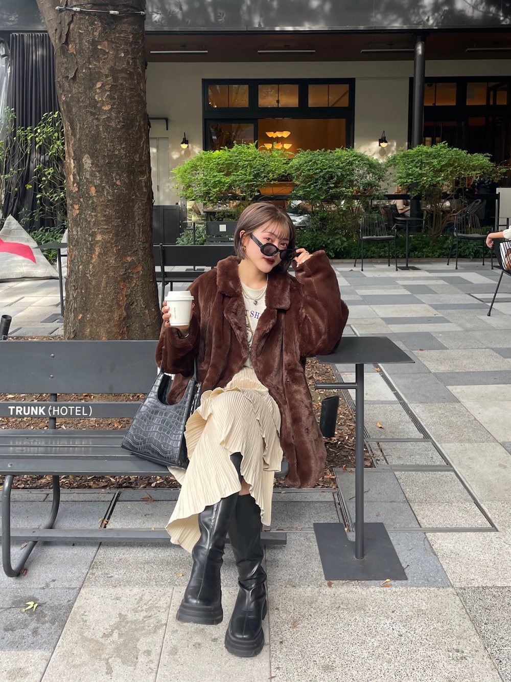 ブラック系のブーツ、ブラウン系のその他アウターを着用したレディースの春コーディネートの2枚目の写真