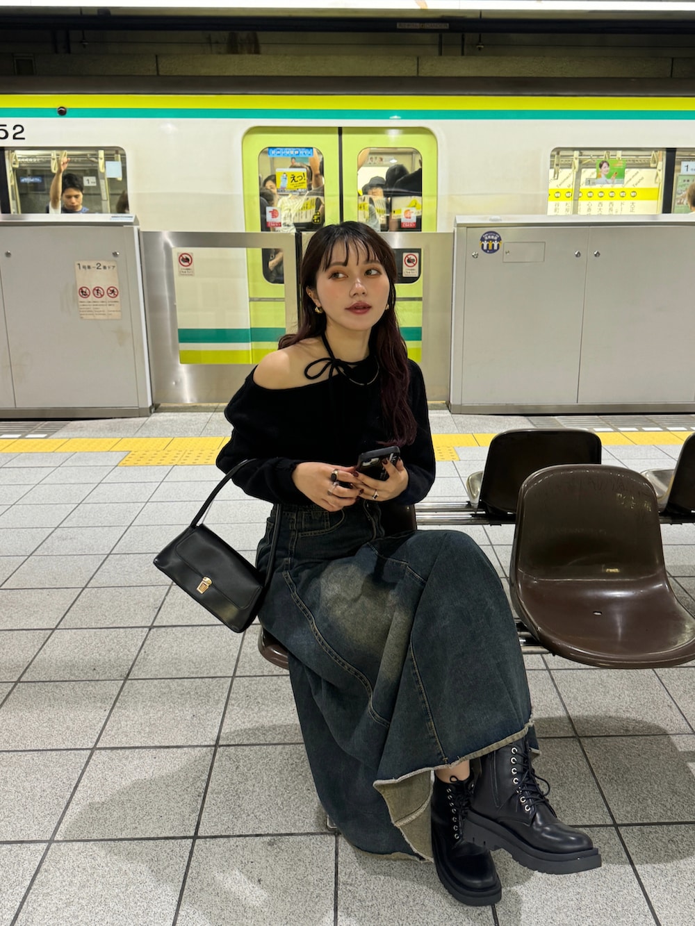 ブラック系のハンドバッグ、ブラック系のブーツを着用したレディースの秋コーディネートの2枚目の写真