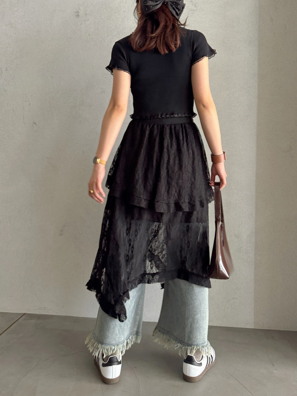 ブラウン系のハンドバッグ、ブラック系のスカート、ブルー系のデニムパンツを着用したレディースの春コーディネートの4枚目の写真