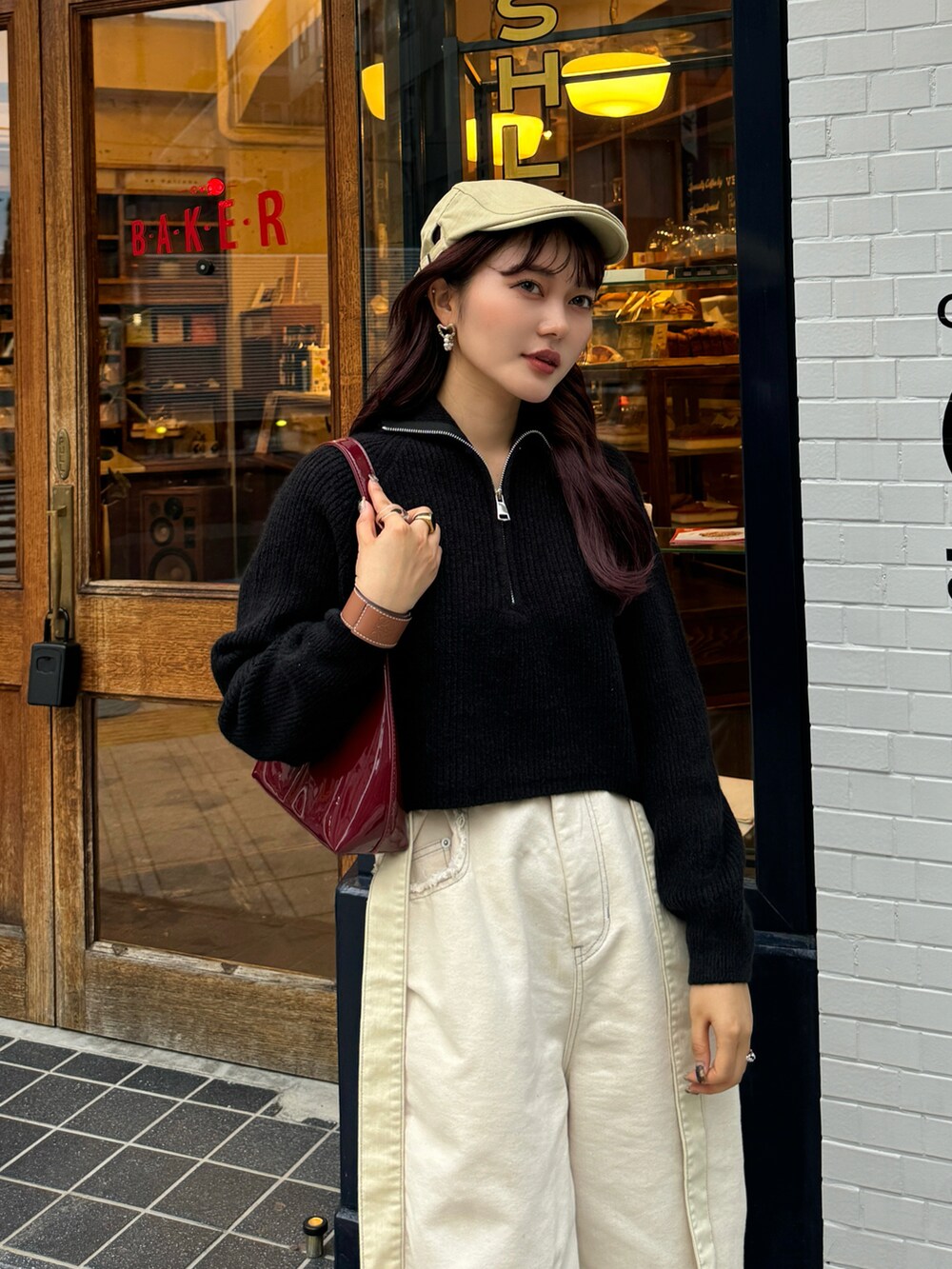 ブラック系のニット/セーター、ホワイト系のデニムパンツ、ベージュ系のスニーカーを着用したレディースの秋コーディネートの5枚目の写真