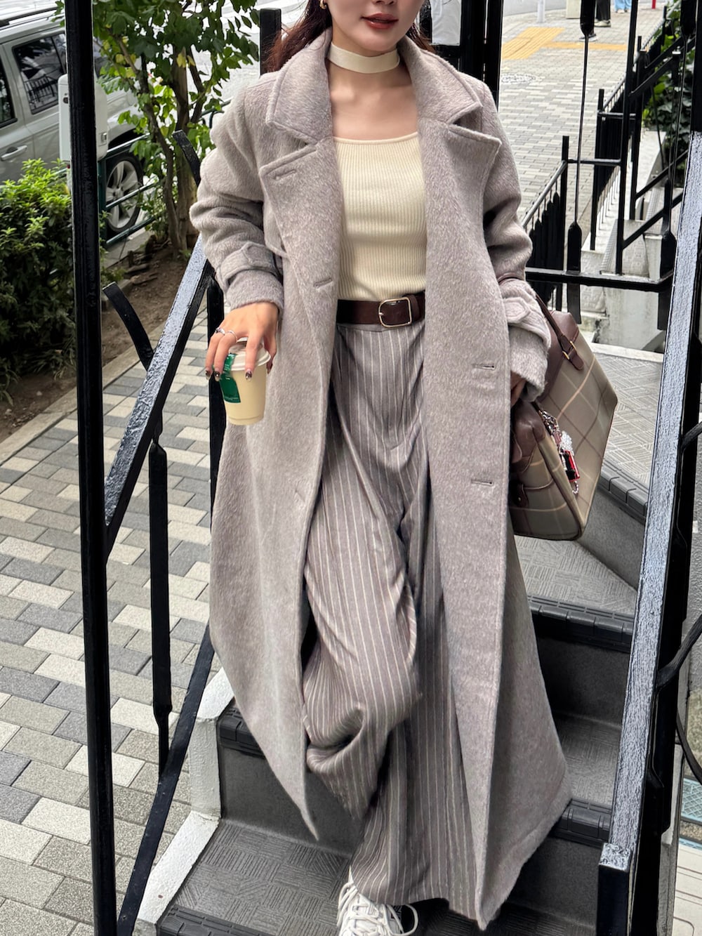 ブラウン系のステンカラーコート、ホワイト系のニット/セーター、ベージュ系のスニーカーを着用したレディースの秋コーディネートの4枚目の写真