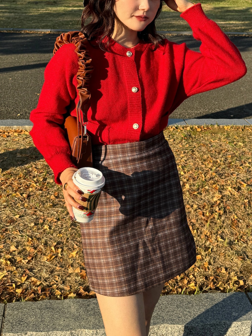 ブラウン系のスカート、レッド系のニット/セーター、ブラック系のブーツを着用したレディースの秋コーディネートの5枚目の写真