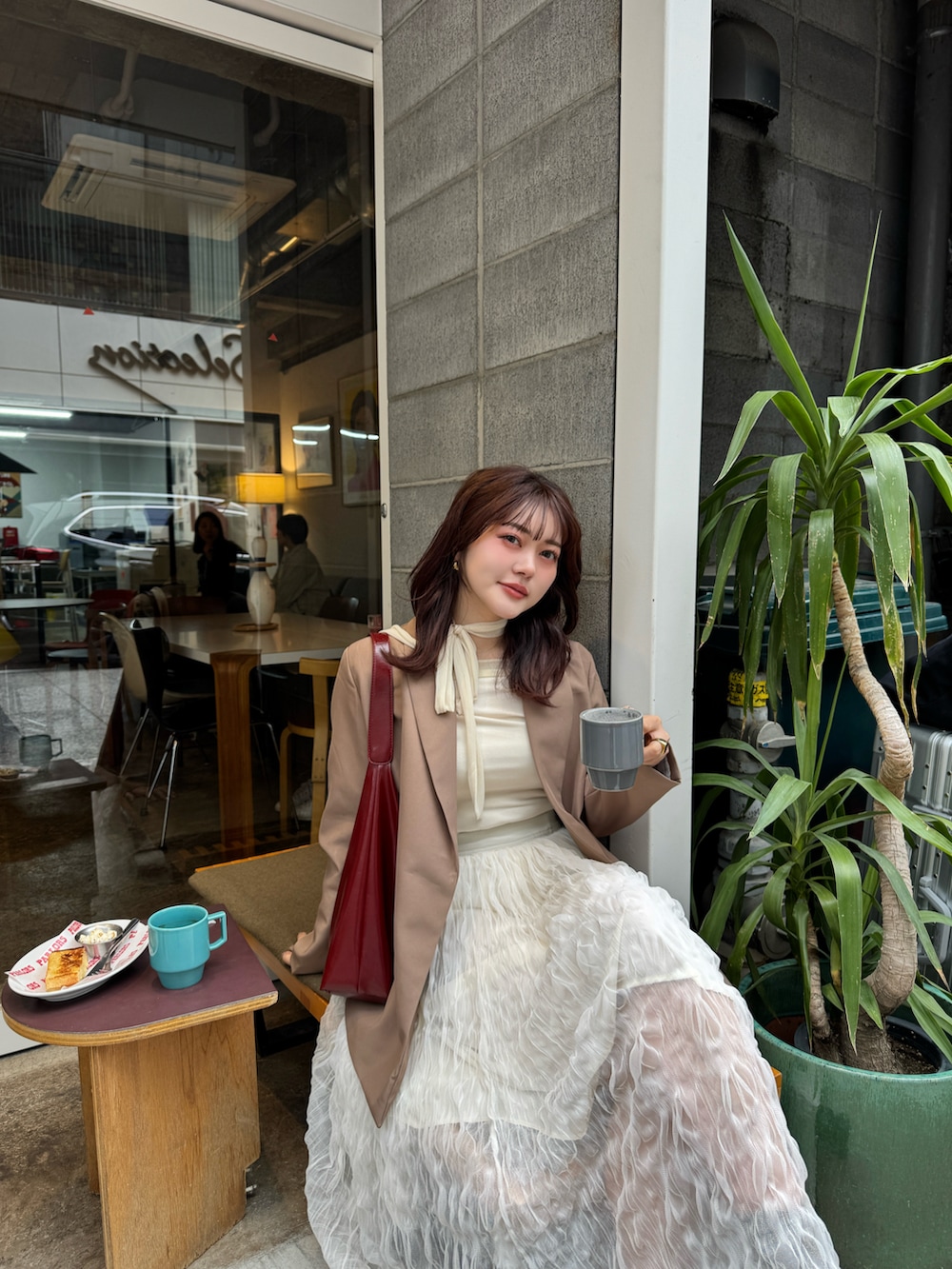 ホワイト系のスカート、ブラウン系のテーラードジャケット、ホワイト系のTシャツ/カットソーを着用したレディースの春コーディネートの2枚目の写真