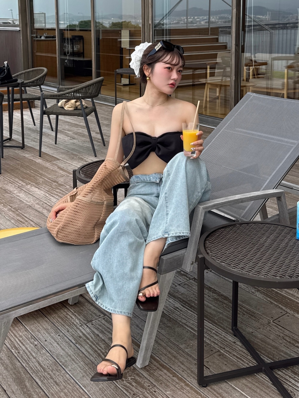 ブルー系のデニムパンツ、ブラウン系のサンダルを着用したレディースの夏コーディネートの2枚目の写真