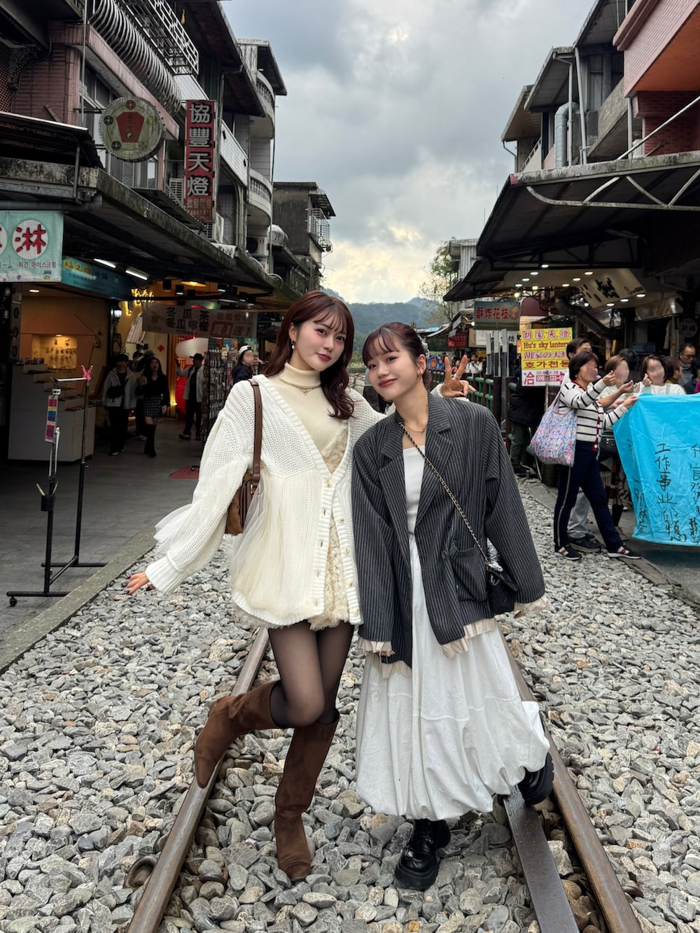 グレー系のテーラードジャケット、ホワイト系のカーディガン/ボレロ、ブラウン系のブーツを着用したレディースの冬コーディネートの4枚目の写真