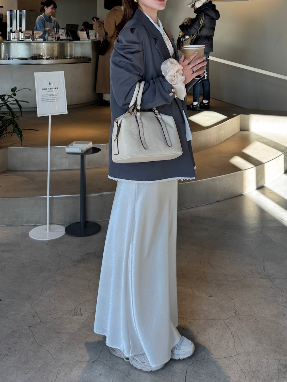 ホワイト系のスカート、ホワイト系のボストンバッグ、グレー系のテーラードジャケットを着用したレディースの春コーディネートの2枚目の写真