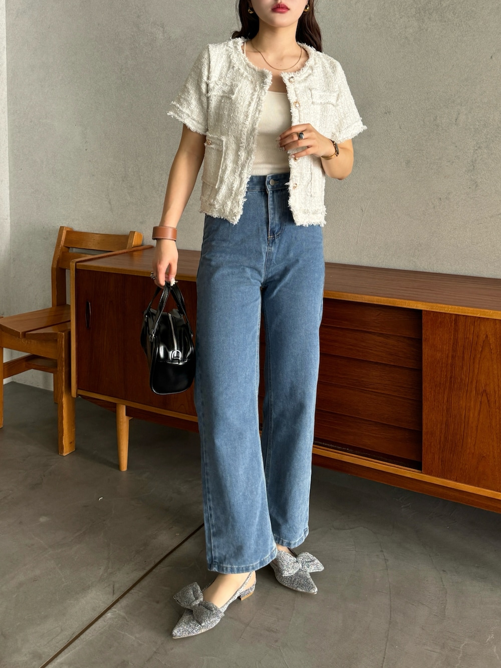 ホワイト系のノーカラージャケット、ブルー系のデニムパンツ、シルバー系のパンプスを着用したレディースの春コーディネートの2枚目の写真