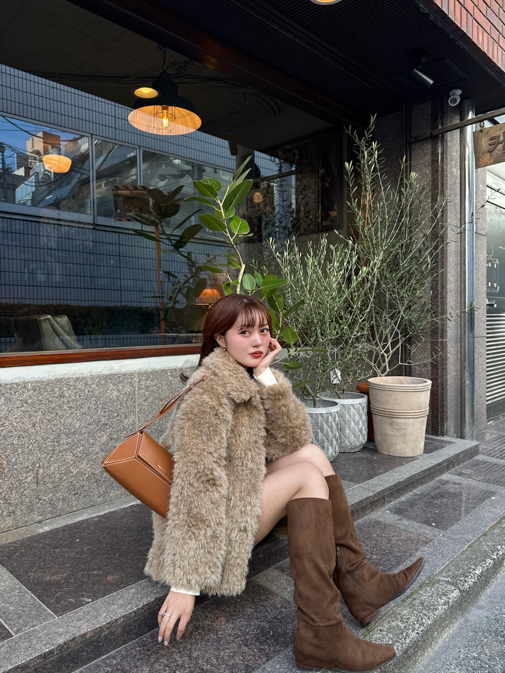 ブラウン系のブーツ、ブラウン系のショルダーバッグ、ベージュ系のカバーオールを着用したレディースの冬コーディネートの4枚目の写真