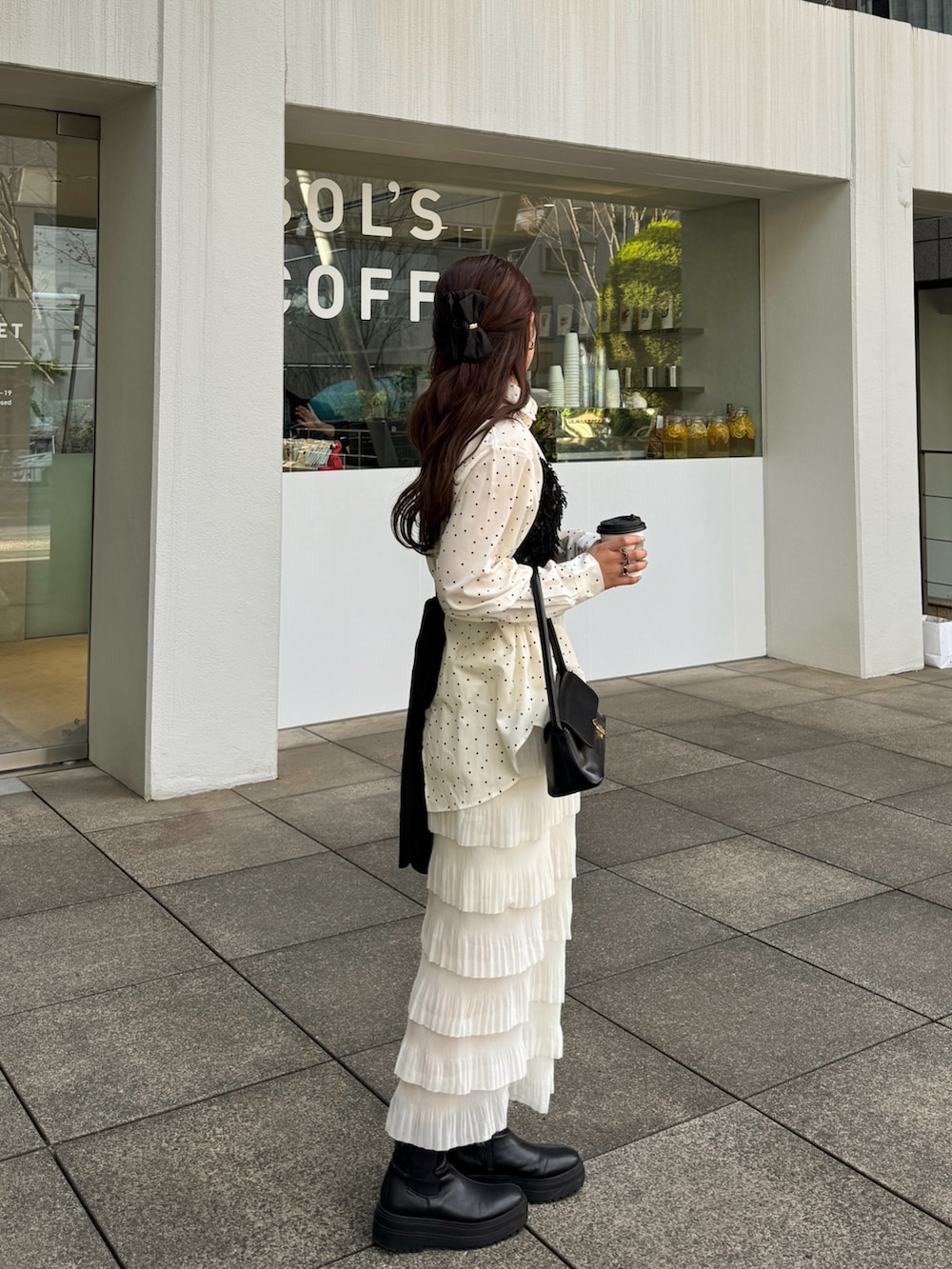 ブラック系のハンドバッグ、ブラック系のトップス、ホワイト系のシャツ/ブラウスを着用したレディースの冬コーディネートの4枚目の写真