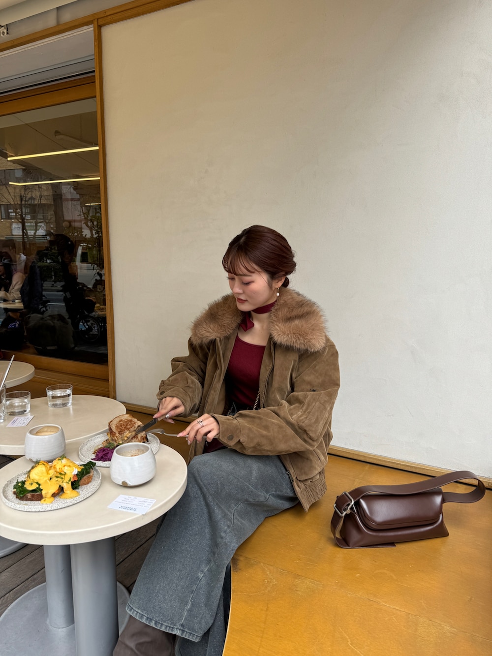 ブルー系のデニムパンツ、ベージュ系のブルゾン、レッド系のニット/セーターを着用したレディースの冬コーディネートの2枚目の写真