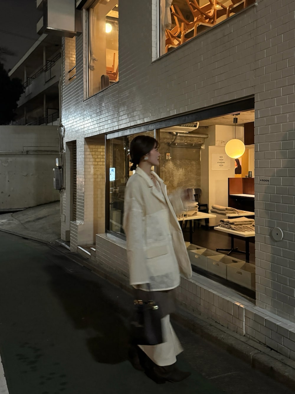 ホワイト系のテーラードジャケット、ブラウン系のブーツを着用したレディースの春コーディネートの2枚目の写真