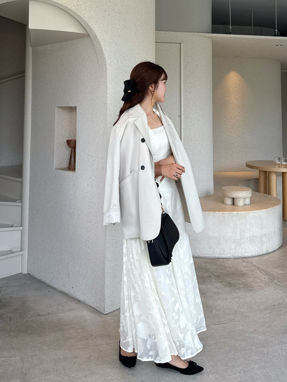 ホワイト系のワンピース、ブラック系のハンドバッグを着用したレディースの春コーディネートの3枚目の写真