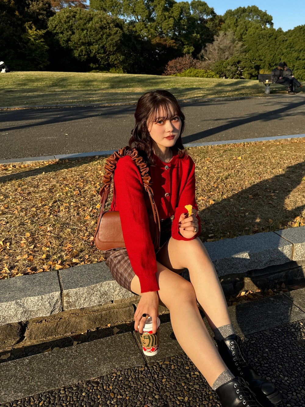 ブラウン系のスカート、レッド系のニット/セーター、ブラック系のブーツを着用したレディースの秋コーディネートの3枚目の写真