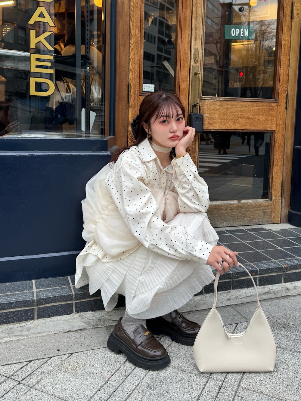 レッド系のハンドバッグ、ベージュ系のスカート、ホワイト系のシャツ/ブラウスを着用したレディースの春コーディネートの4枚目の写真