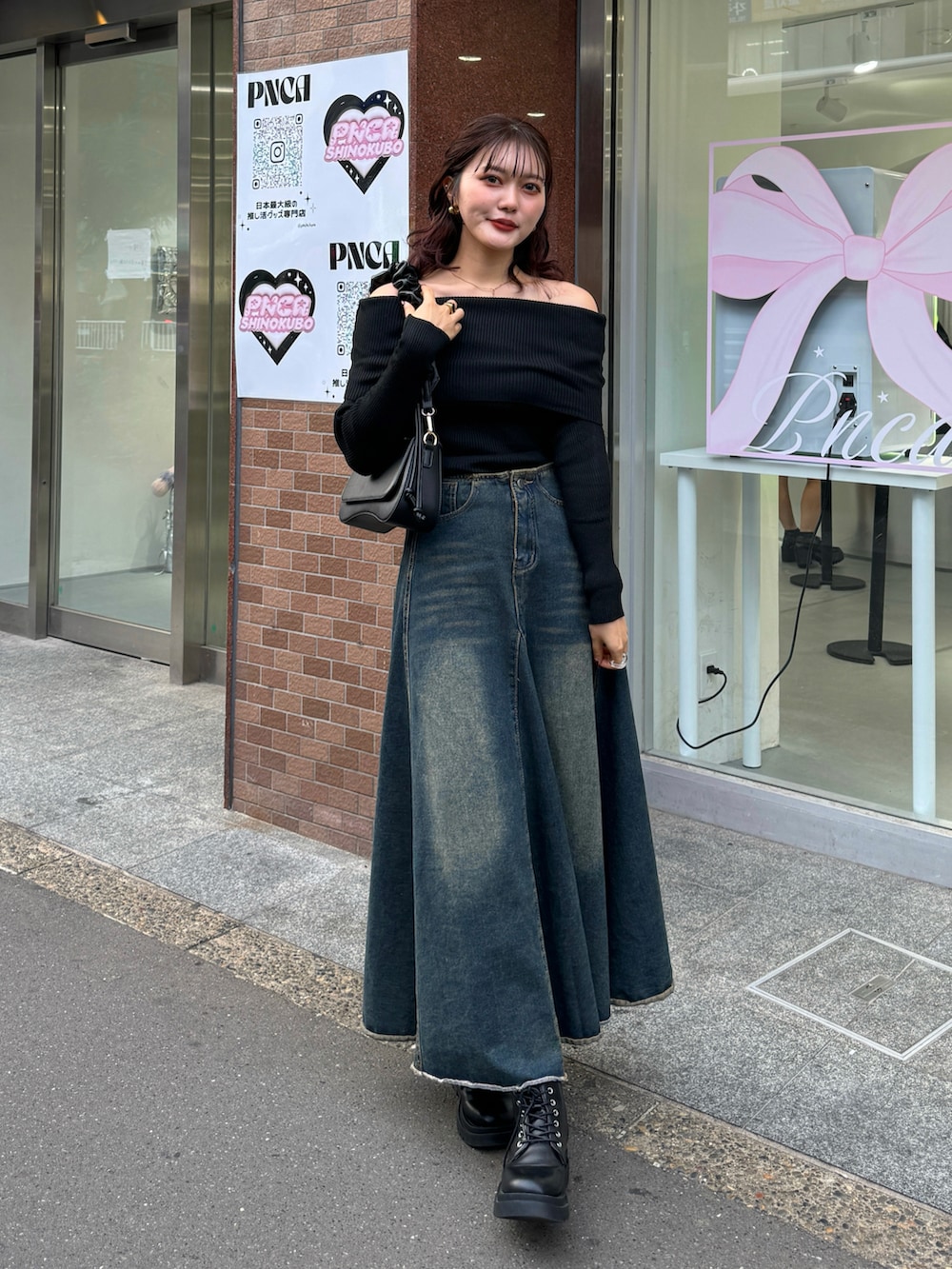 ブラック系のニット/セーター、ブラウン系のハンドバッグ、ブラック系のブーツを着用したレディースの秋コーディネートの2枚目の写真