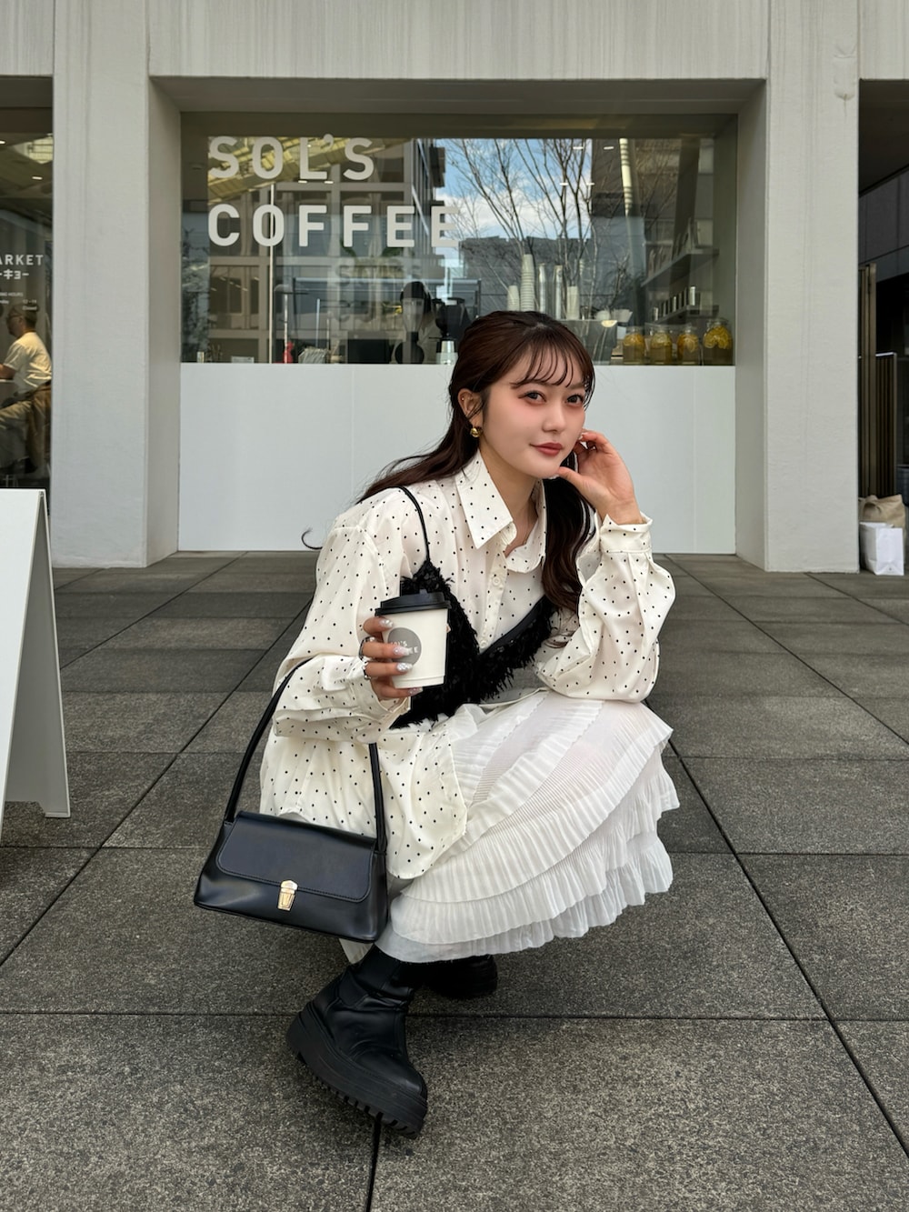 ブラック系のハンドバッグ、ブラック系のトップス、ホワイト系のシャツ/ブラウスを着用したレディースの冬コーディネートの3枚目の写真