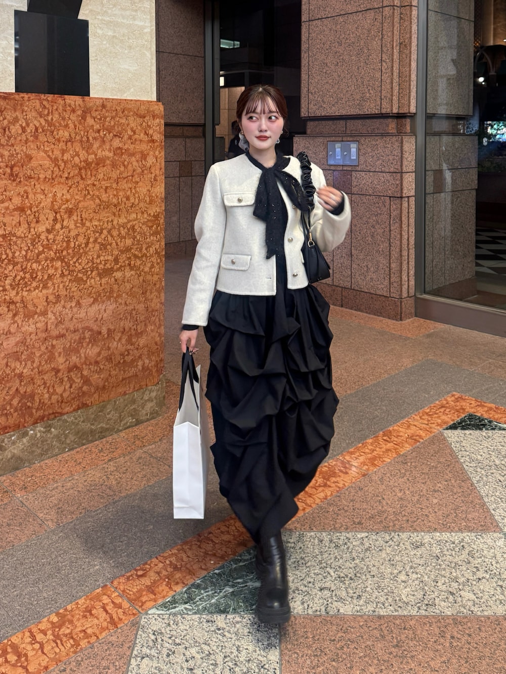 ブラック系のスカート、ピンク系のノーカラージャケット、ブラック系のシャツ/ブラウスを着用したレディースの秋コーディネートの2枚目の写真