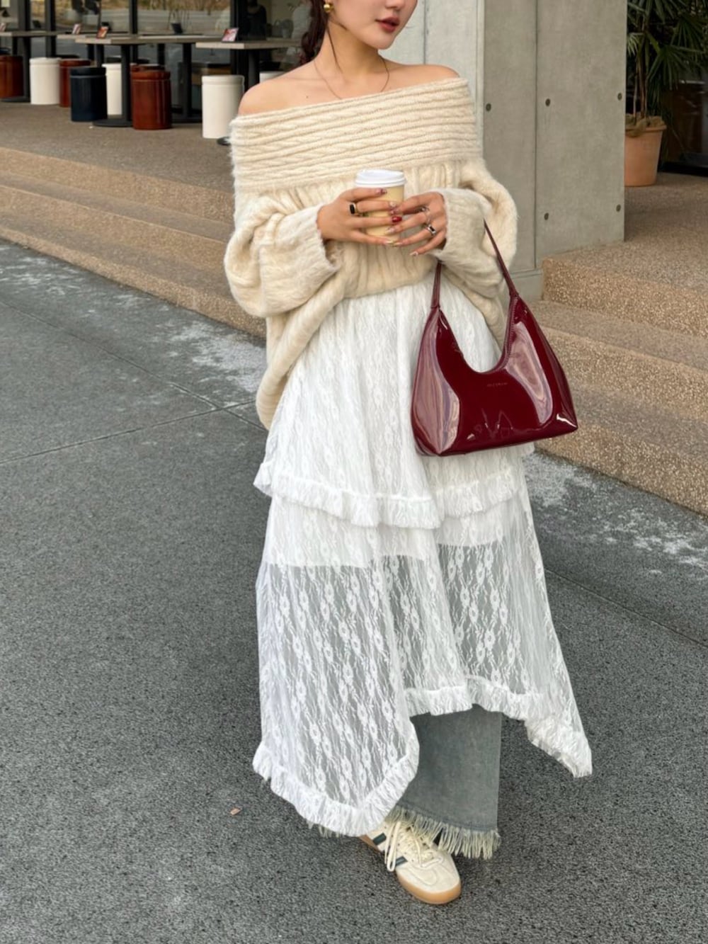 レッド系のハンドバッグ、ブルー系のデニムパンツを着用したレディースの冬コーディネートの5枚目の写真