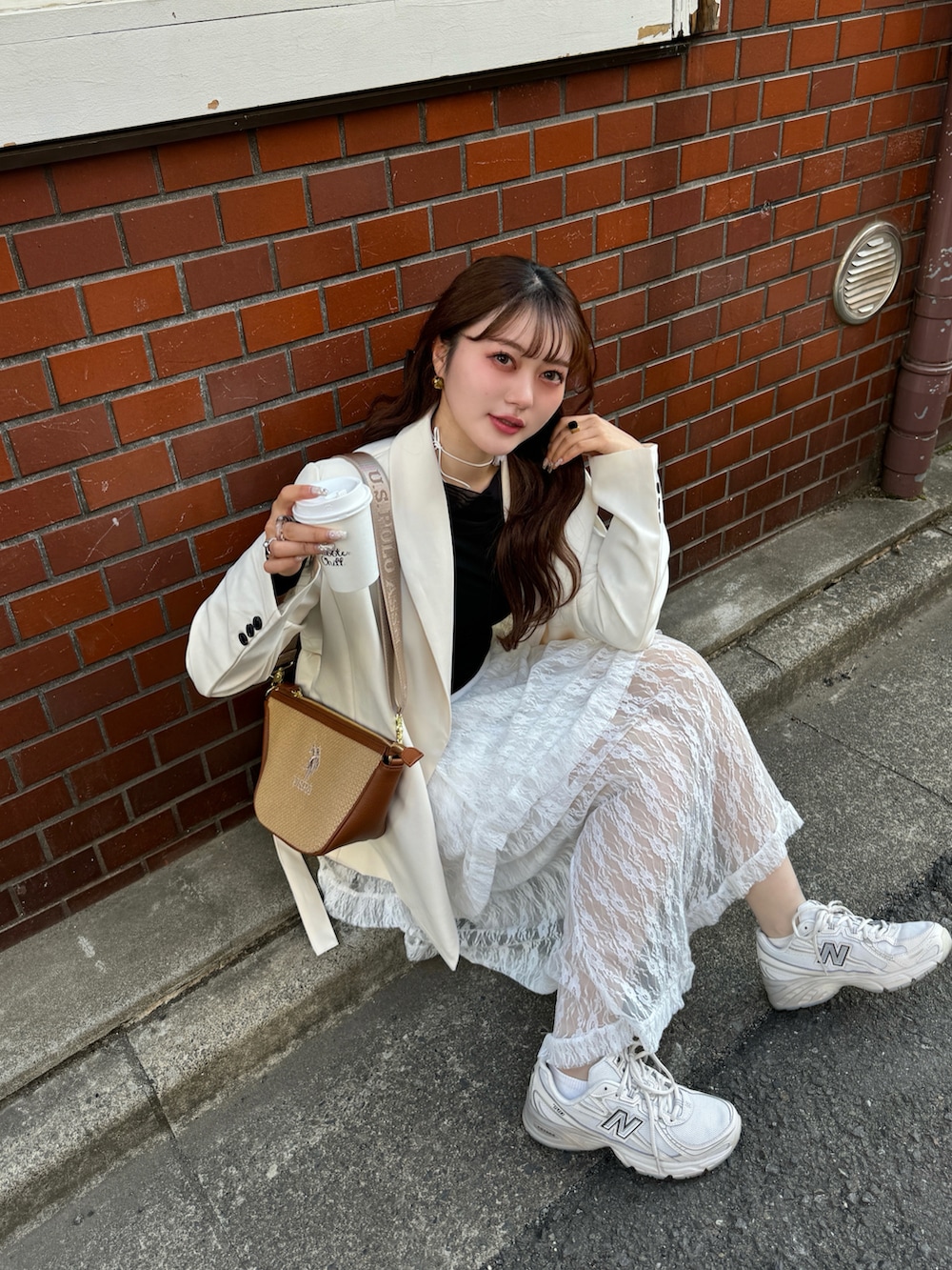 ブラウン系のショルダーバッグ、ホワイト系のスカート、ベージュ系のスニーカーを着用したレディースの春コーディネートの3枚目の写真