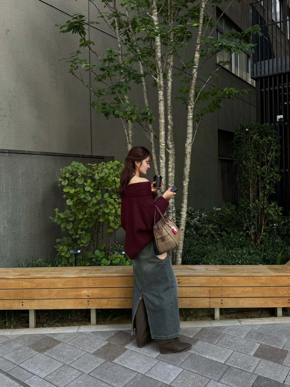 レッド系のニット/セーター、ブルー系のデニムスカート、ブラウン系のブーツを着用したレディースの秋コーディネートの4枚目の写真