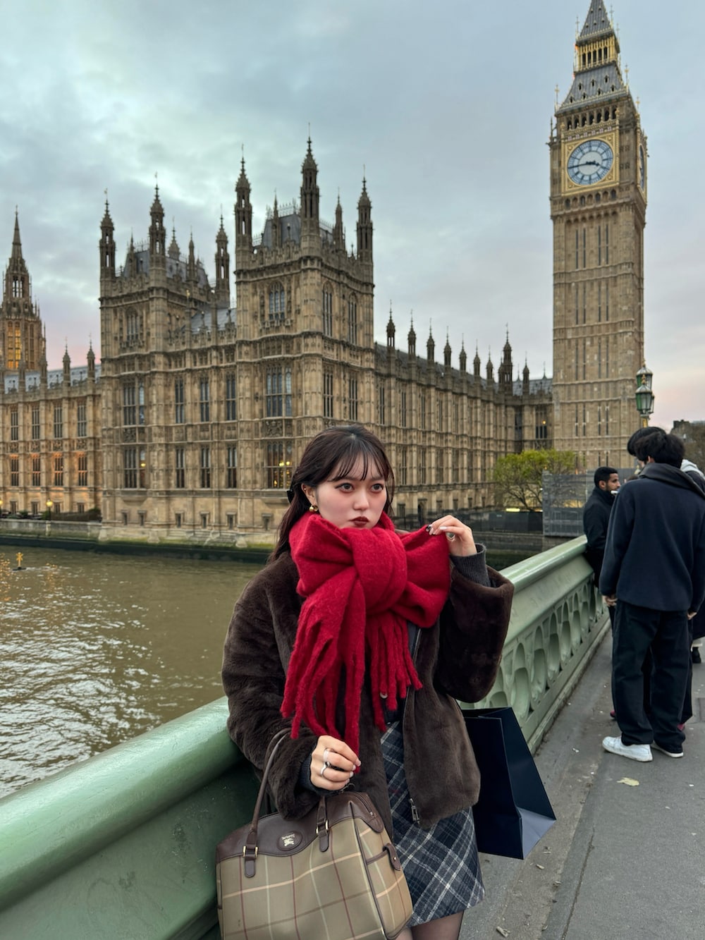 ブラック系のスカート、グリーン系のブルゾン、レッド系のマフラーを着用したレディースの冬コーディネートの2枚目の写真