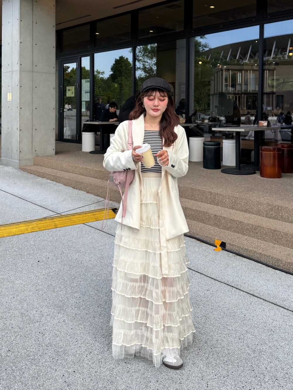 ホワイト系のスカート、ホワイト系のスニーカー、ホワイト系のテーラードジャケットを着用したレディースの春コーディネートの2枚目の写真