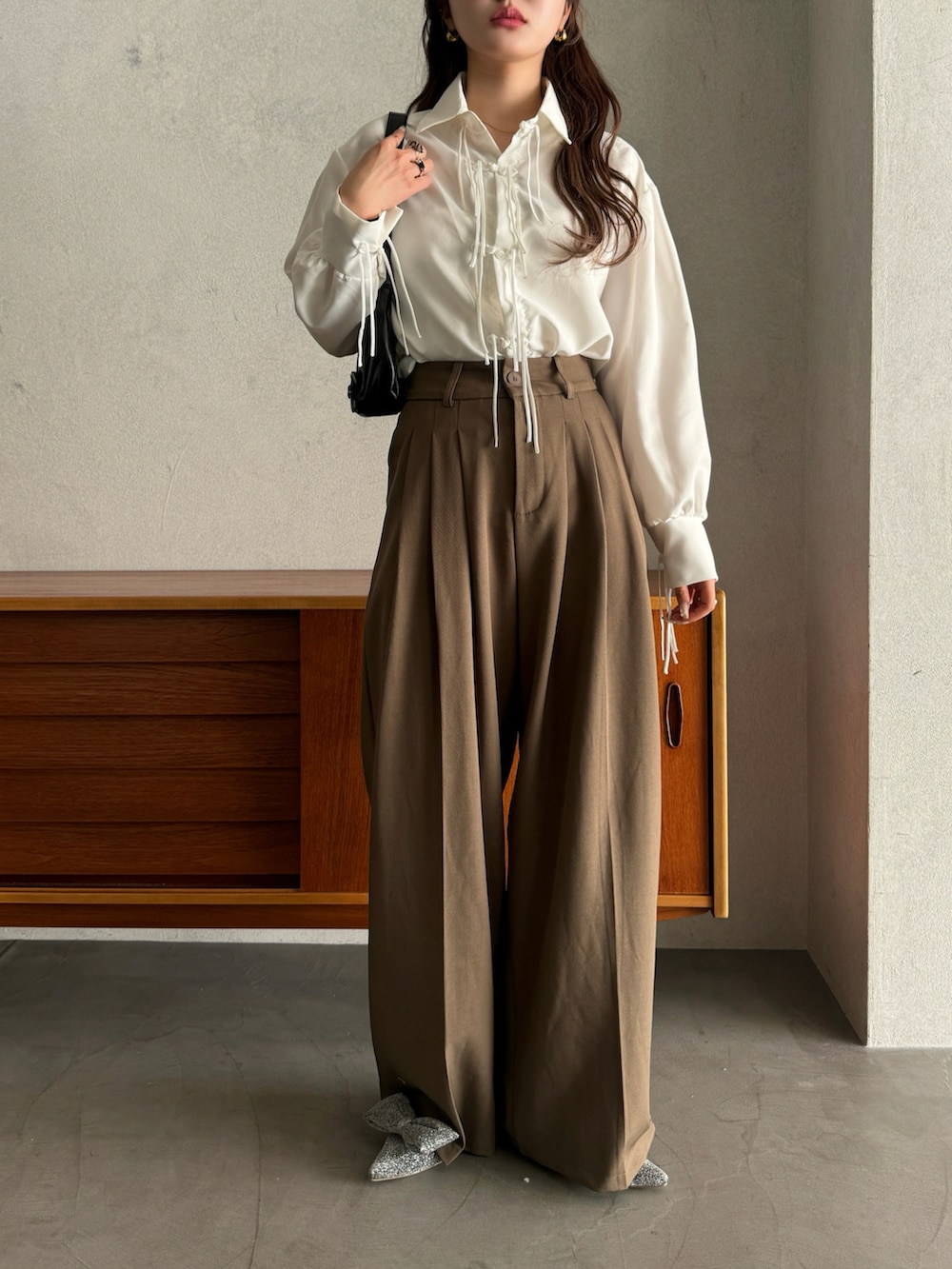 シルバー系のパンプス、ベージュ系のスラックス、ホワイト系のシャツ/ブラウスを着用したレディースの春コーディネートの2枚目の写真