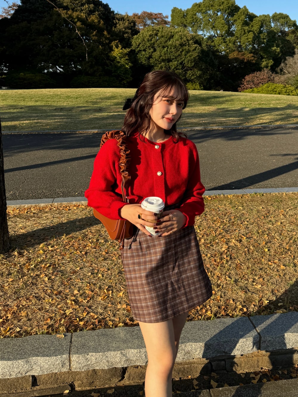 ブラウン系のスカート、レッド系のニット/セーター、ブラック系のブーツを着用したレディースの秋コーディネートの2枚目の写真