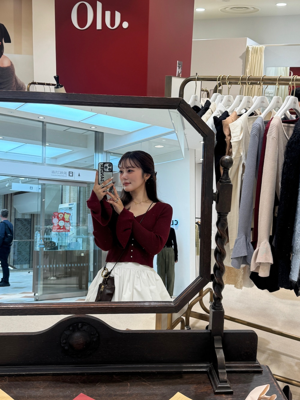 ホワイト系のスカート、レッド系のカーディガン/ボレロ、ブラック系のブーツを着用したレディースの秋コーディネートの2枚目の写真