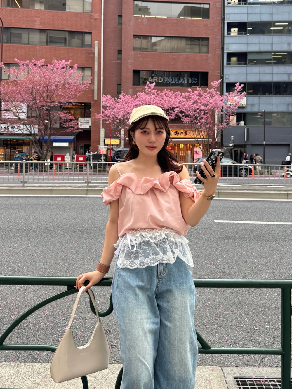 ベージュ系のハンドバッグ、ピンク系のTシャツ/カットソー、ホワイト系のスカートを着用したレディースの春コーディネートの2枚目の写真