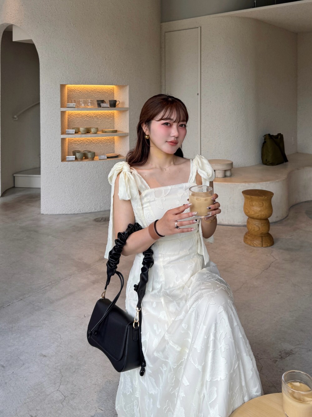 ホワイト系のワンピース、ブラック系のハンドバッグを着用したレディースの春コーディネートの4枚目の写真