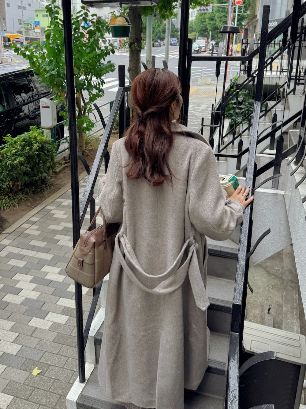 ブラウン系のステンカラーコート、ホワイト系のニット/セーター、ベージュ系のスニーカーを着用したレディースの秋コーディネートの3枚目の写真