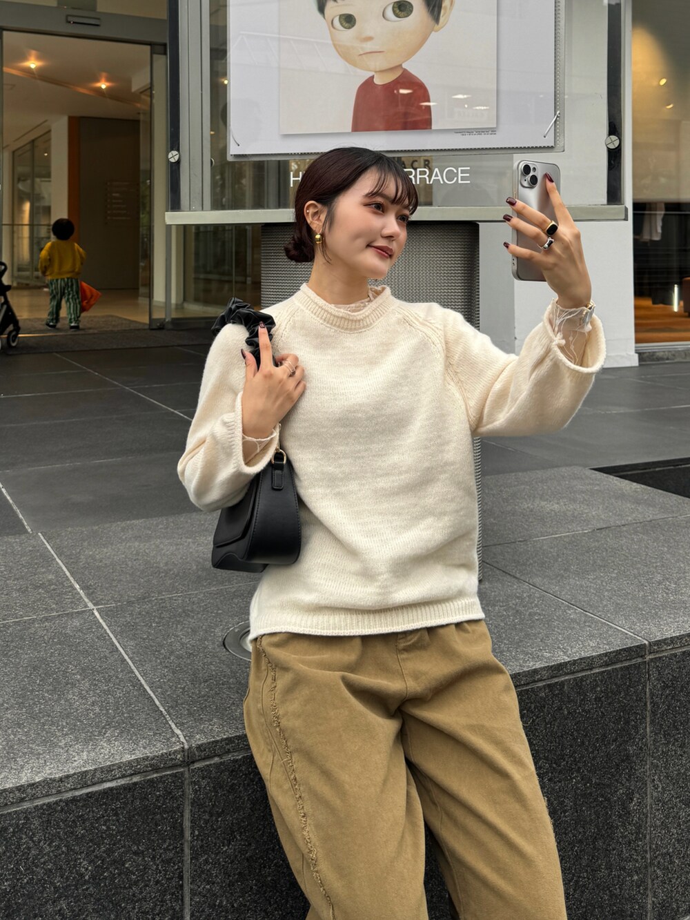 ブラウン系のハンドバッグ、ホワイト系のニット/セーターを着用したレディースの秋コーディネートの4枚目の写真