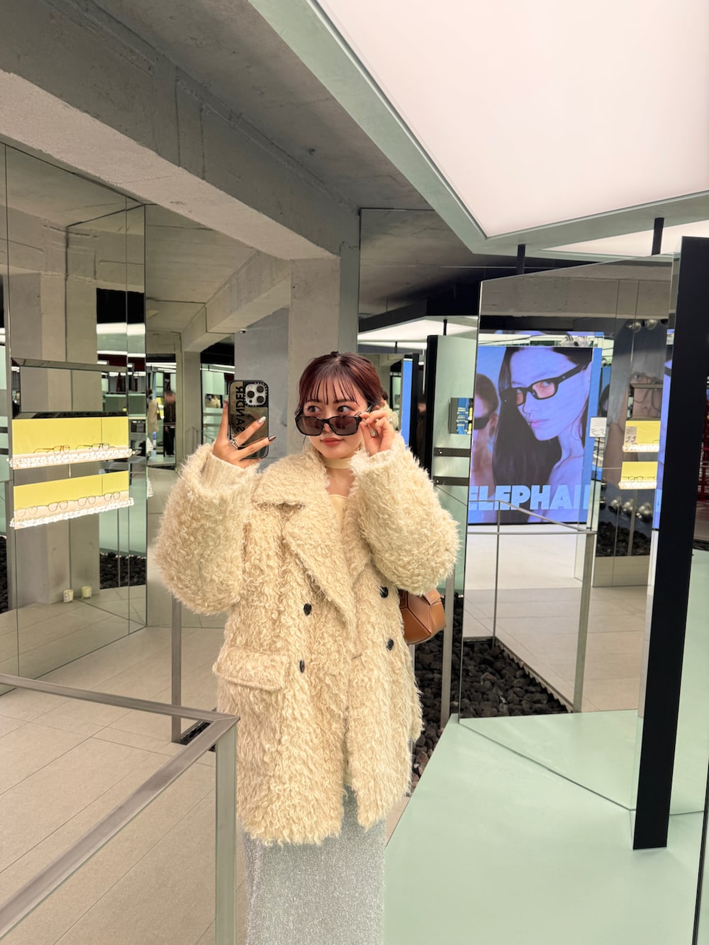 ホワイト系のその他アウター、シルバー系のスカート、ブラウン系のブーツを着用したレディースの秋コーディネートの2枚目の写真