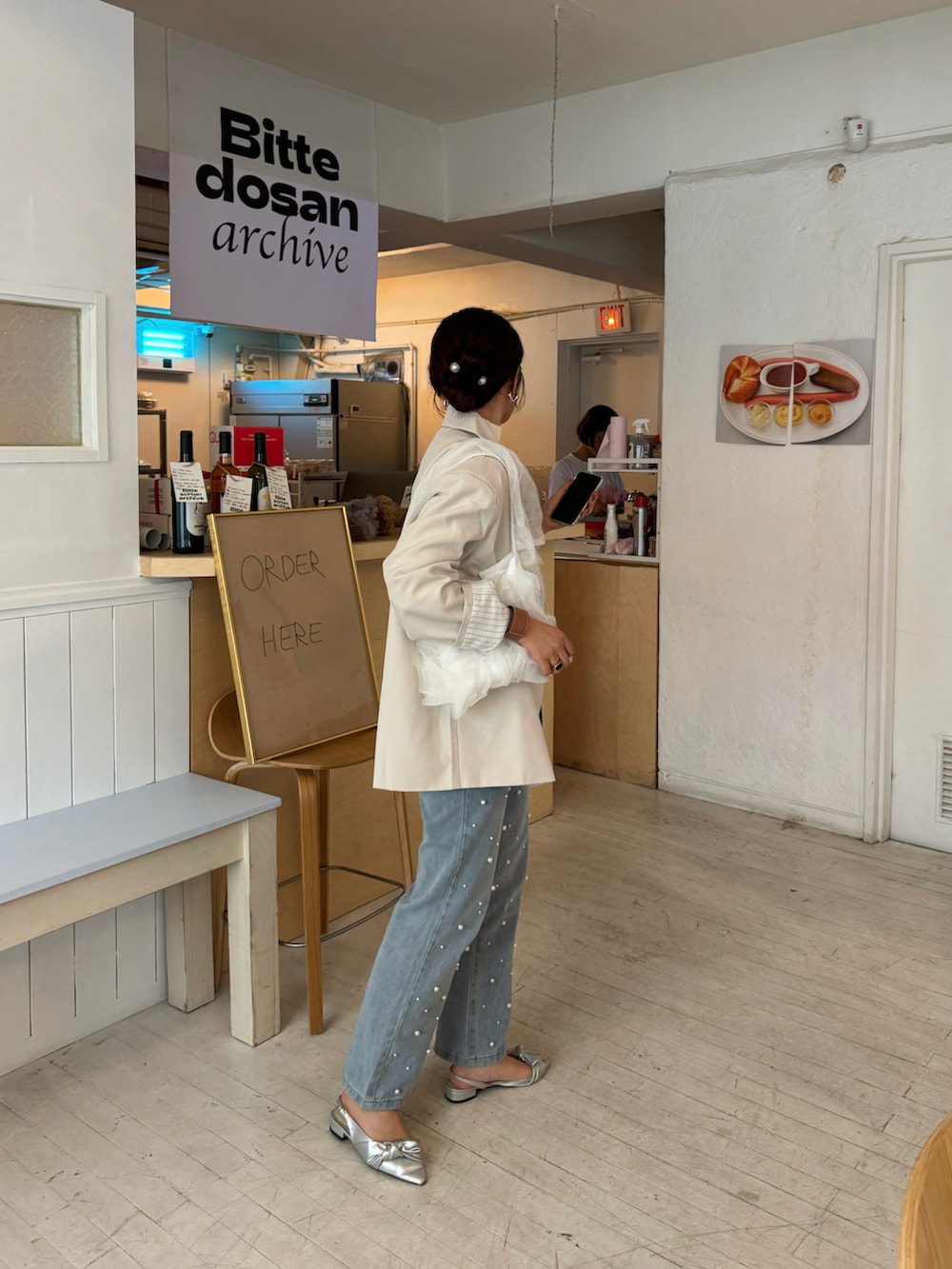 ホワイト系のテーラードジャケット、ブルー系のデニムパンツ、ホワイト系のハンドバッグを着用したレディースの秋コーディネートの4枚目の写真