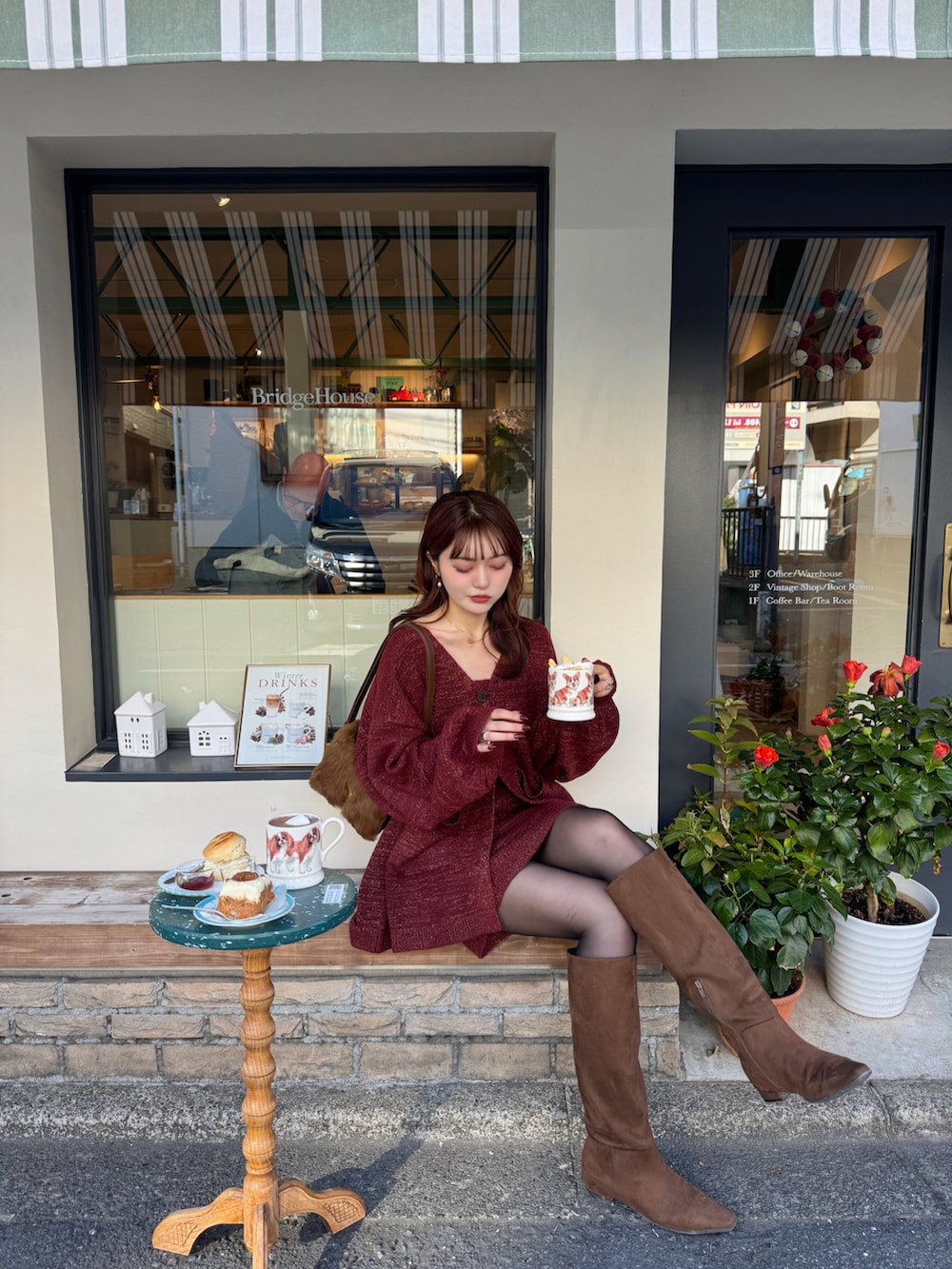 レッド系のアンサンブル、ブラウン系のブーツを着用したレディースの冬コーディネートの2枚目の写真