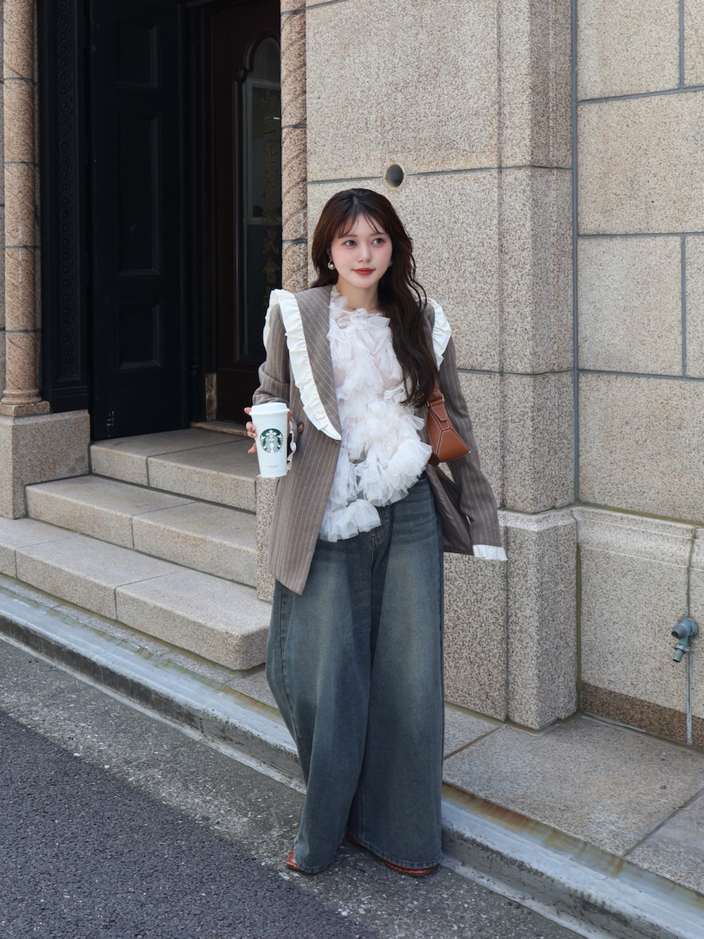 ブルー系のデニムパンツ、ベージュ系のテーラードジャケット、ブラウン系のショルダーバッグを着用したレディースの夏コーディネートの5枚目の写真