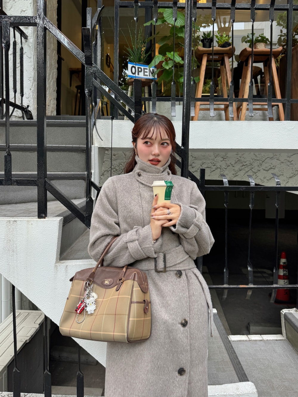 ブラウン系のステンカラーコート、ホワイト系のニット/セーター、ベージュ系のスニーカーを着用したレディースの秋コーディネートの2枚目の写真