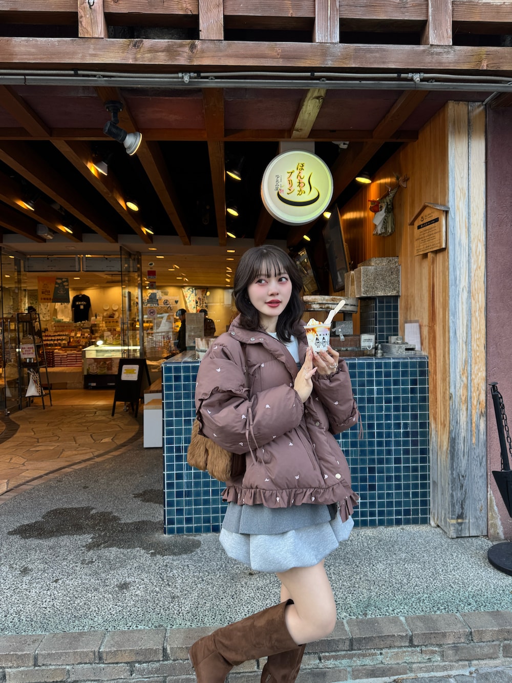 グレー系のスカート、ブラウン系のブーツを着用したレディースの冬コーディネートの2枚目の写真